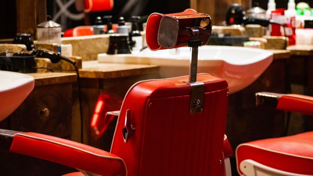Empty vintage-style red barber chairs in a styled shop