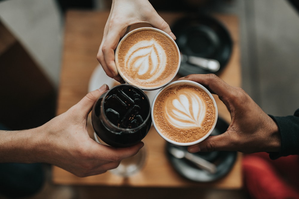 Two people clinking latte cups in a cafe