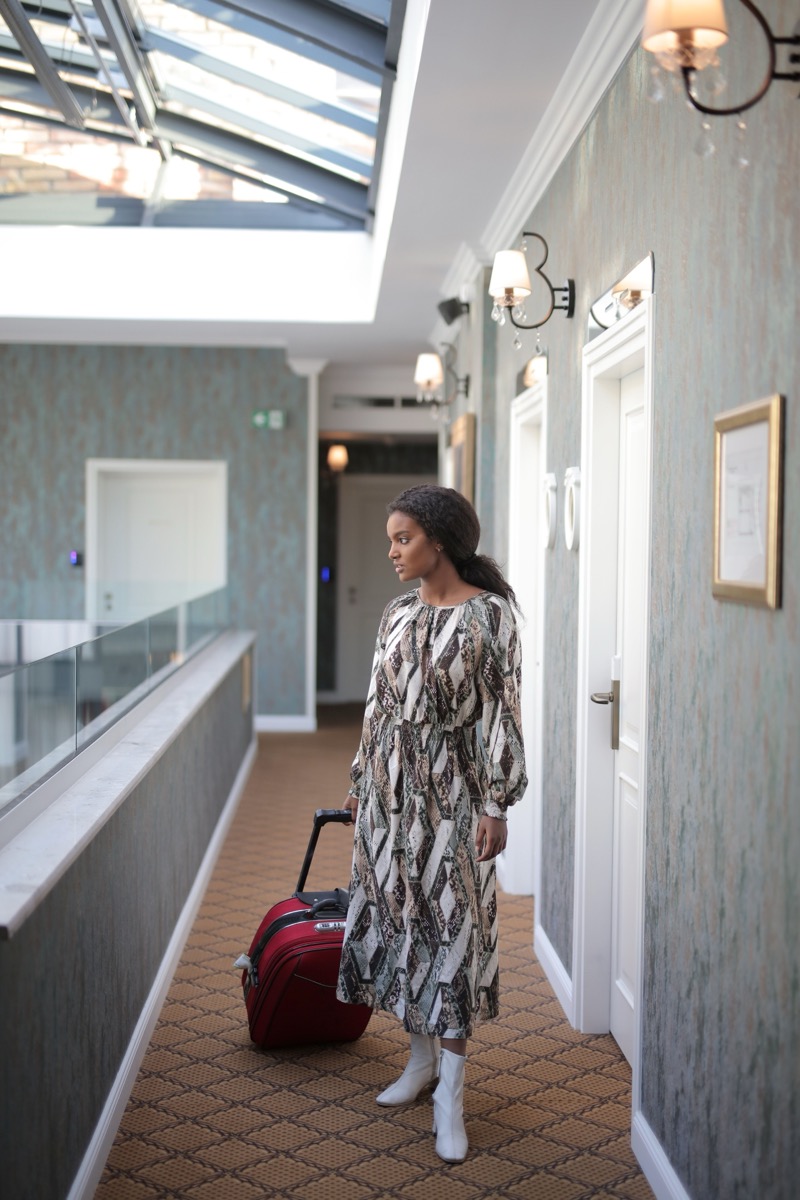 A traveler pulling luggage through a hotel corridor